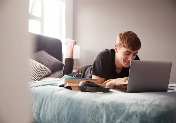Student On Laptop On Bed